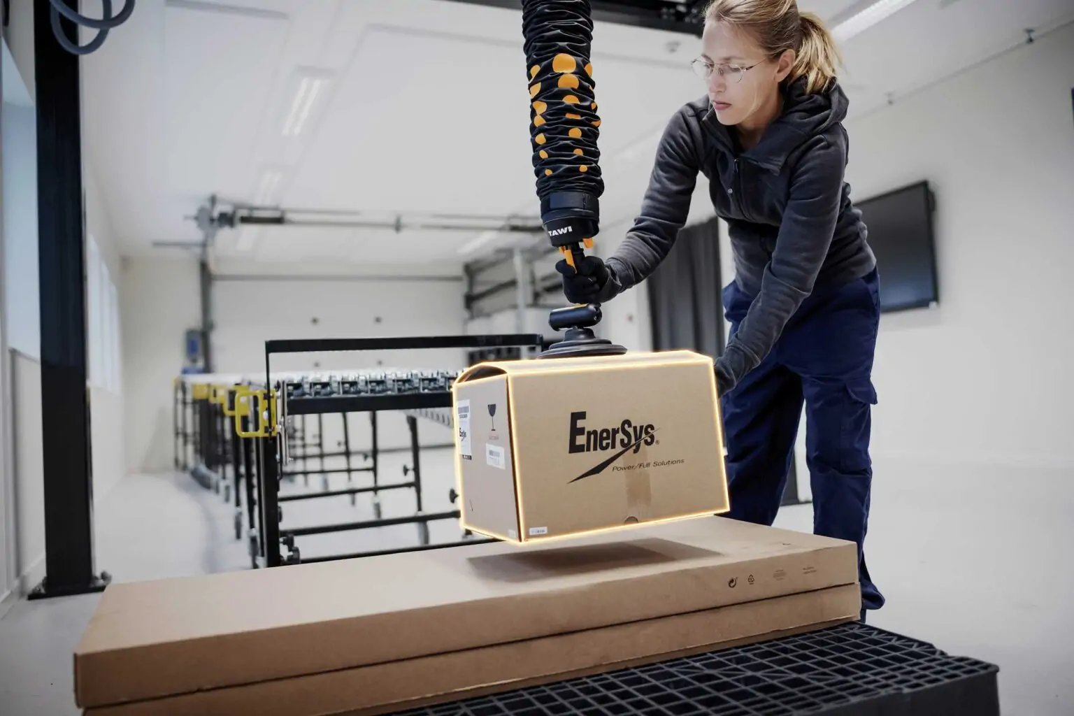 Man in logistics warehouse using vacuum lifter for fast box handling