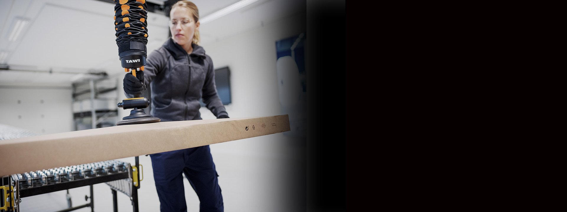Man in logistics warehouse using vacuum lifter for fast box handling