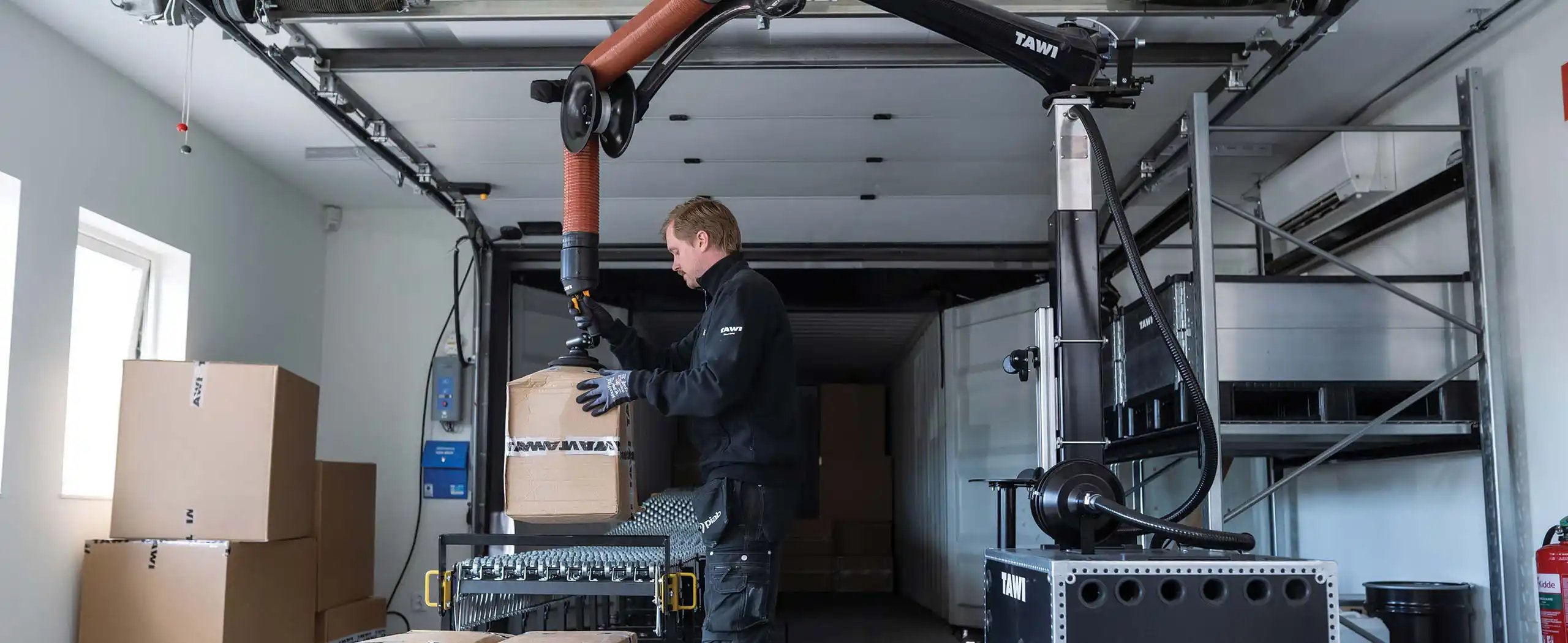 Man in logistics warehouse using vacuum lifter for fast box handling