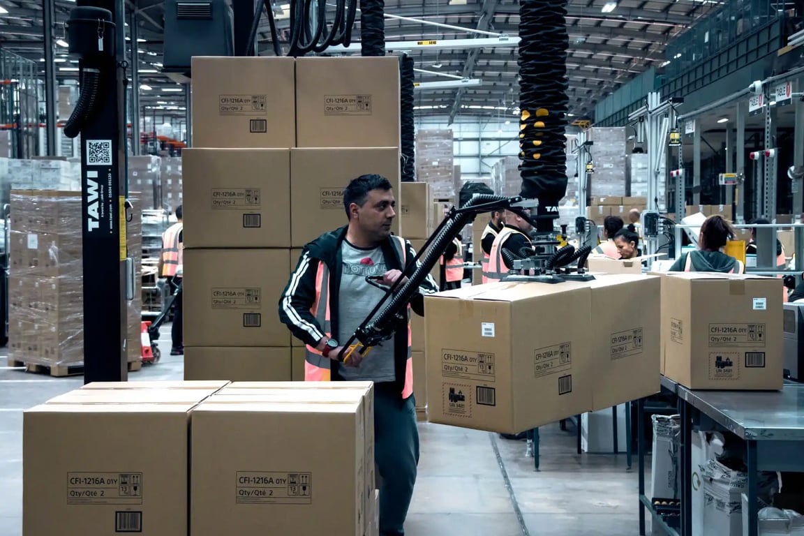 Hombre utilizando un elevador por vacío TAWI para el paletizado al final de línea