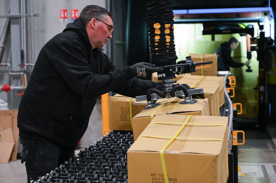 Opérateur manipulant des charges depuis un convoyeur