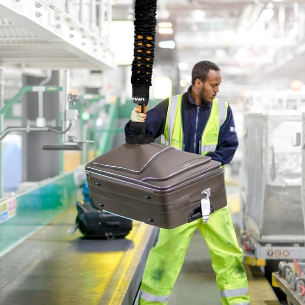 Flughafenpersonal hebt Gepäck mit einem Vakuumheber von TAWI
