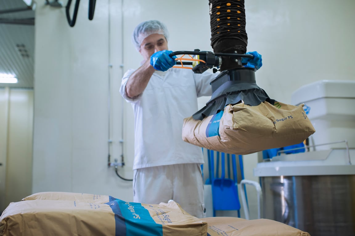Hombre usando soluciones de elevación ergonómicas TAWI en entorno de producción de alimentos