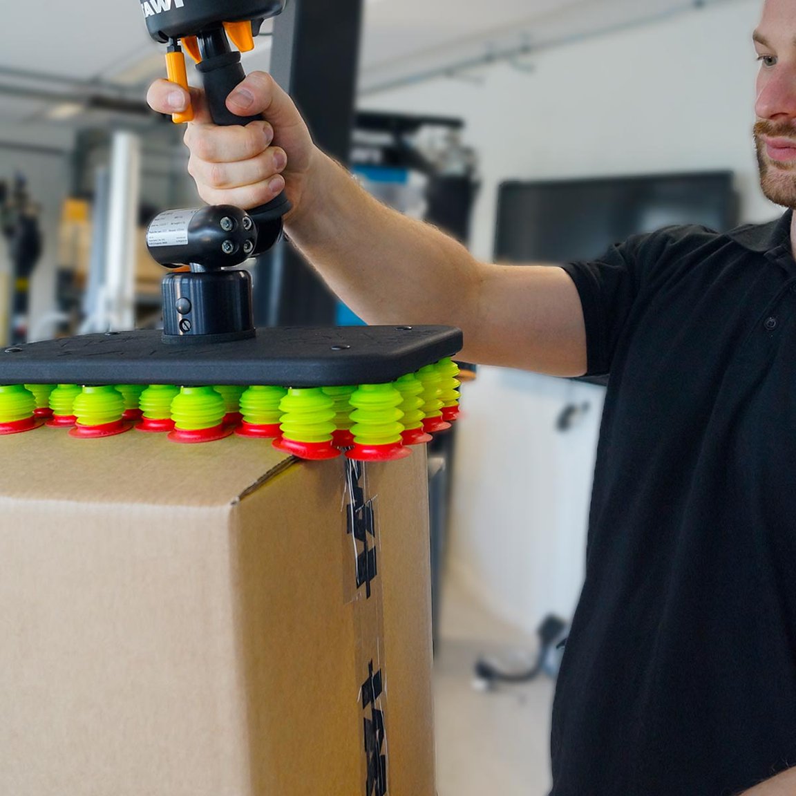 Man using TAWI FlexiGrip tool for vacuum lifter to lift boxes