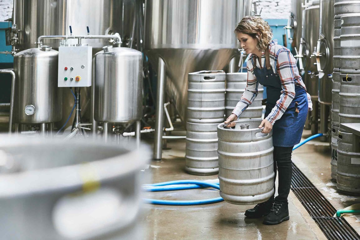 Mujer elevando manualmente barriles pesados en la industria de bebidas
