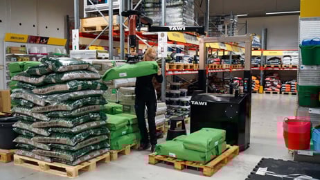 Female warehouse worker lifting large sacks with TAWI Mobile Order Picker