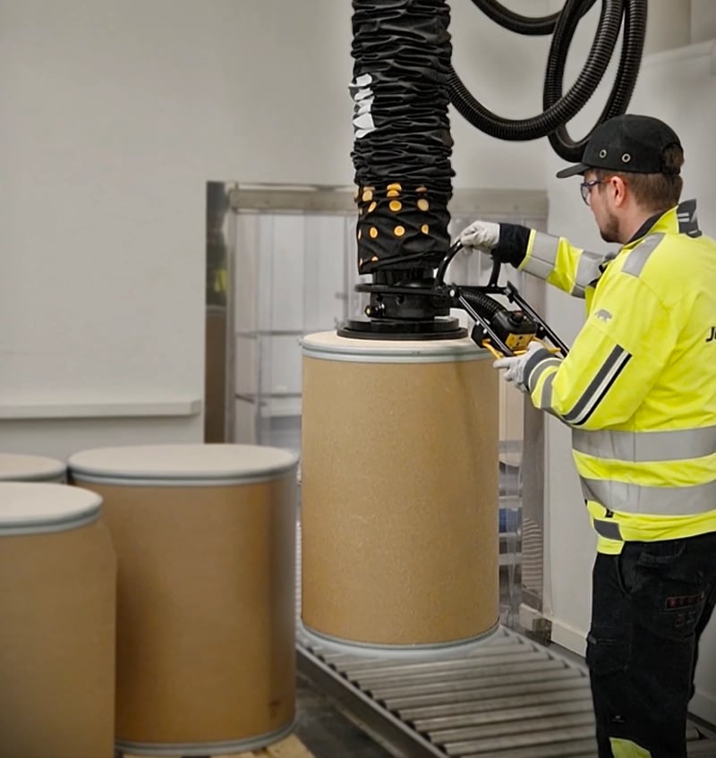 TAWI-oplossingen voor het hanteren van vaten in actie op de magazijnvloer. Zware dozen worden moeiteloos getild, waardoor de fysieke belasting voor de medewerker aanzienlijk wordt verminderd.