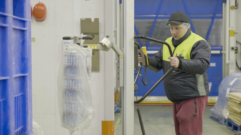 A person uses a TAWI lifting trolley to handle a reel/roll
