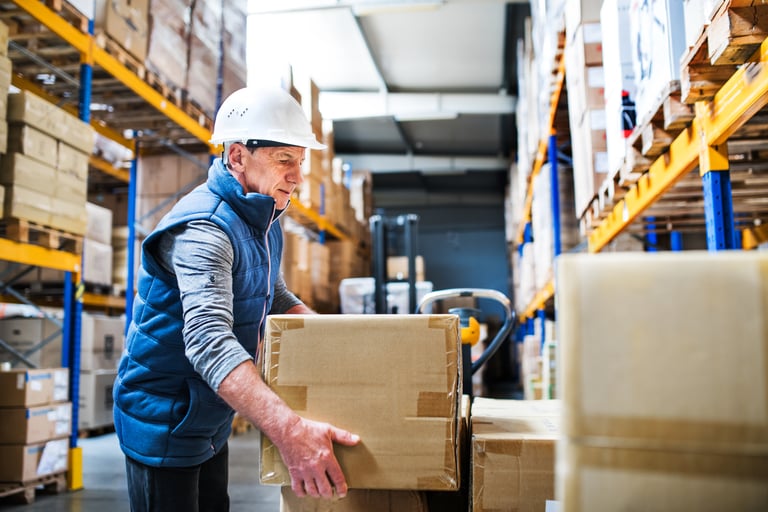   An operator manually lifting a box, executing one of the five most common manual handling tasks in a warehouse.