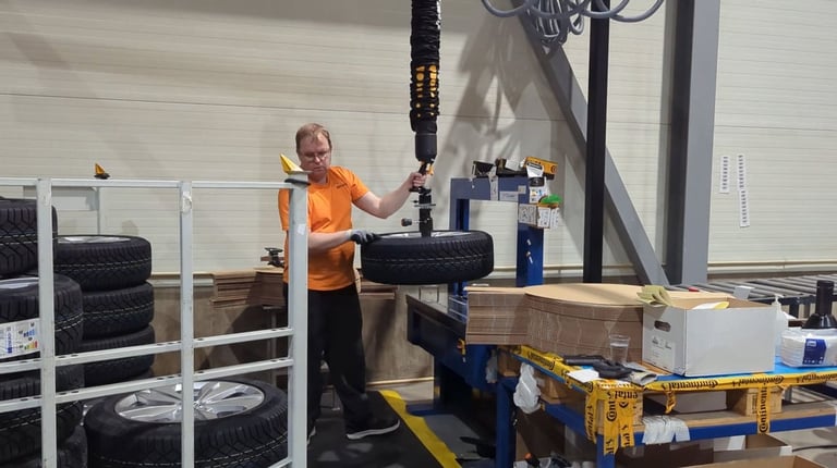 Worker lifting tyres with tawi lifting equipment