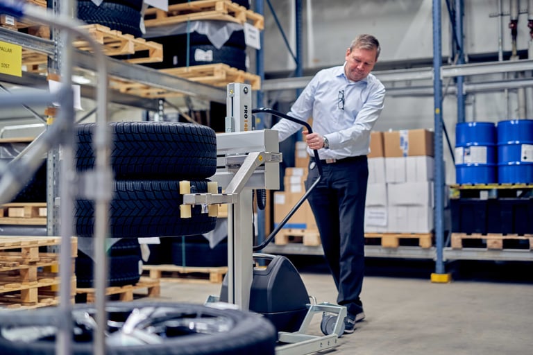 Trabalhador usando os carrinhos TAWI para mover os pneus no armazém