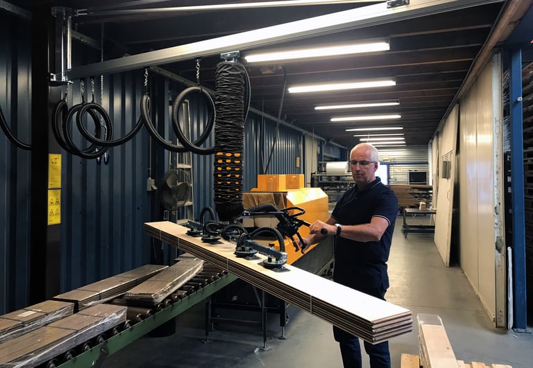 a worker lifting a wood sheet with a vacuum lifter