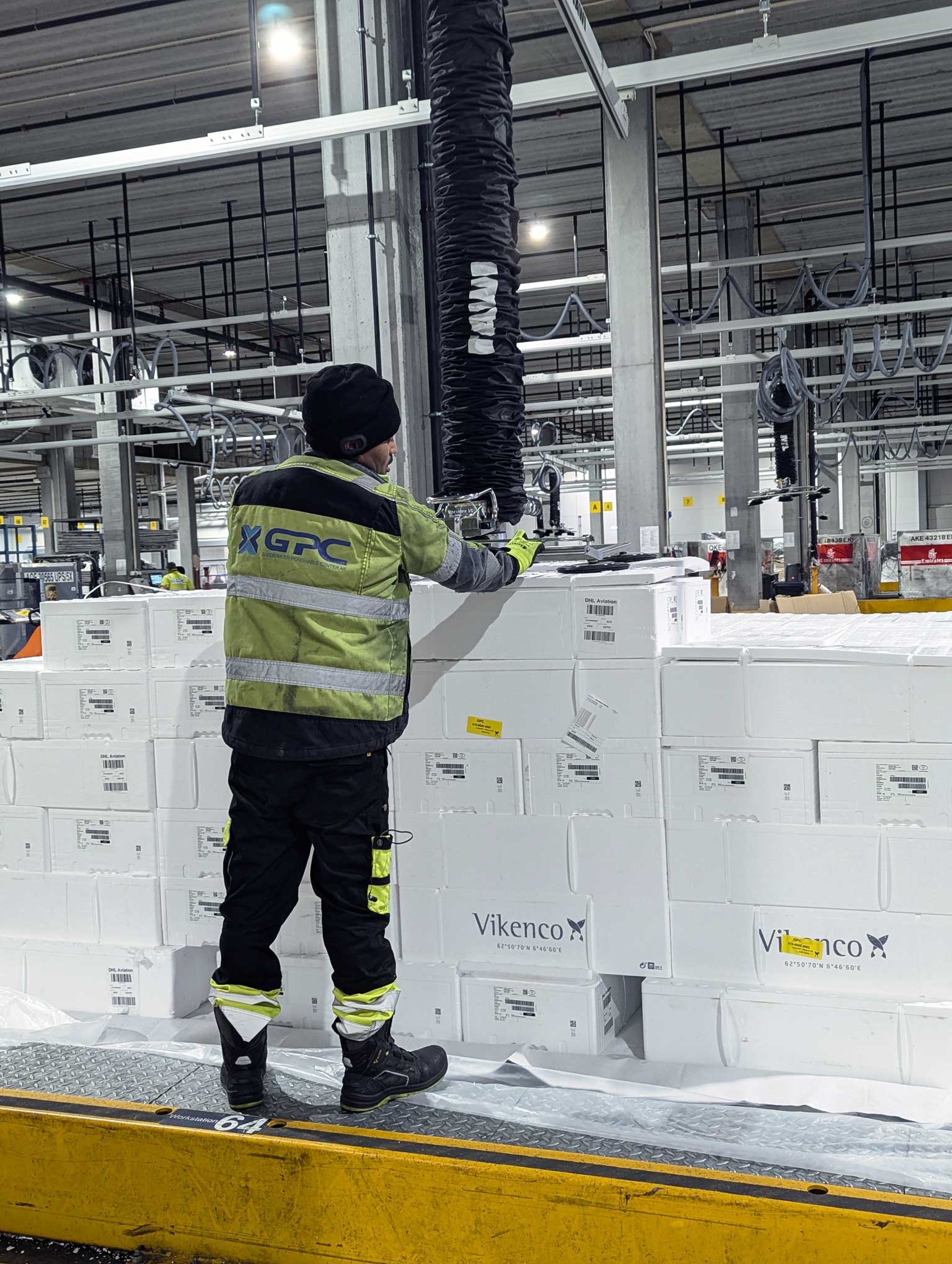 Mies nostaa kalalaatikoita kylmäketjuvarastossa TAWI-vakuuminostimella