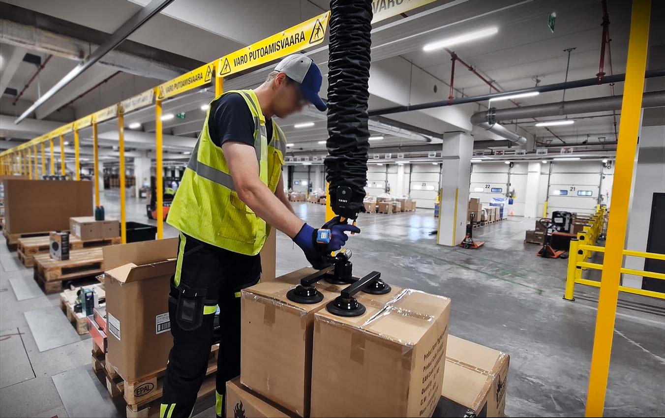 Warehouse worker at Broman Logistics using TAWI vacuum lifter to palletise boxes