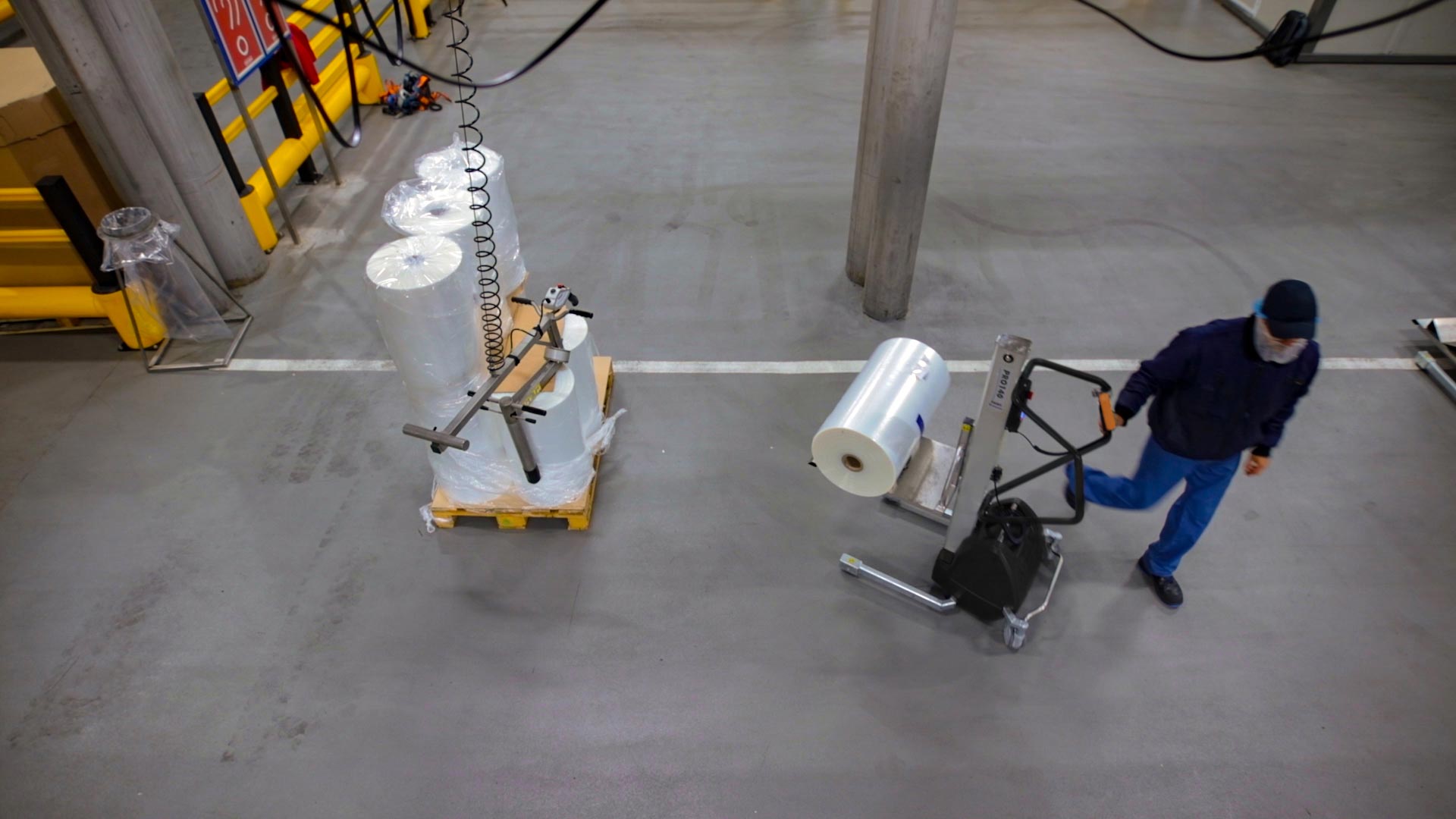 Food production worker using TAWI lifting trolley to move packaging reels