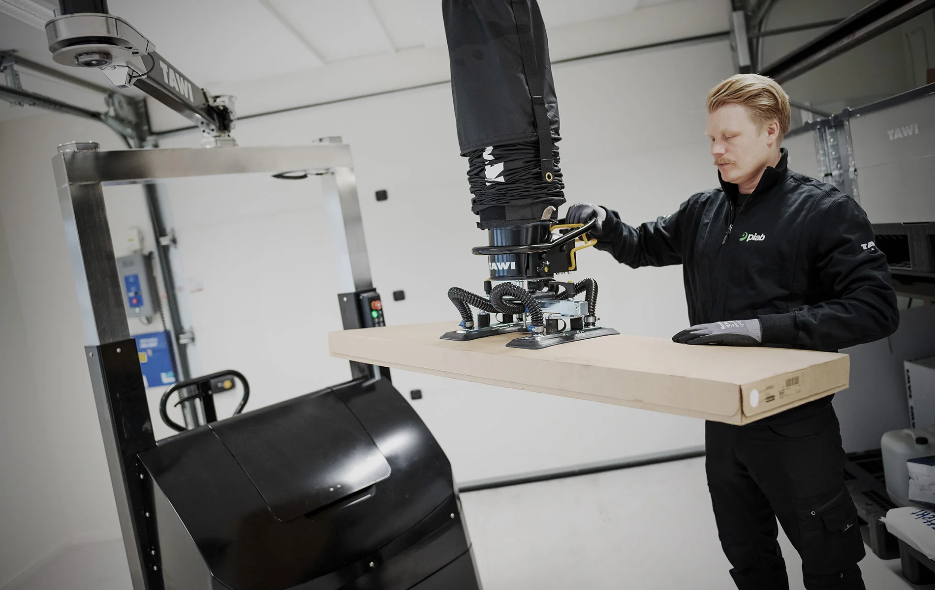Homme soulevant un carton avec un manipulateur mobile