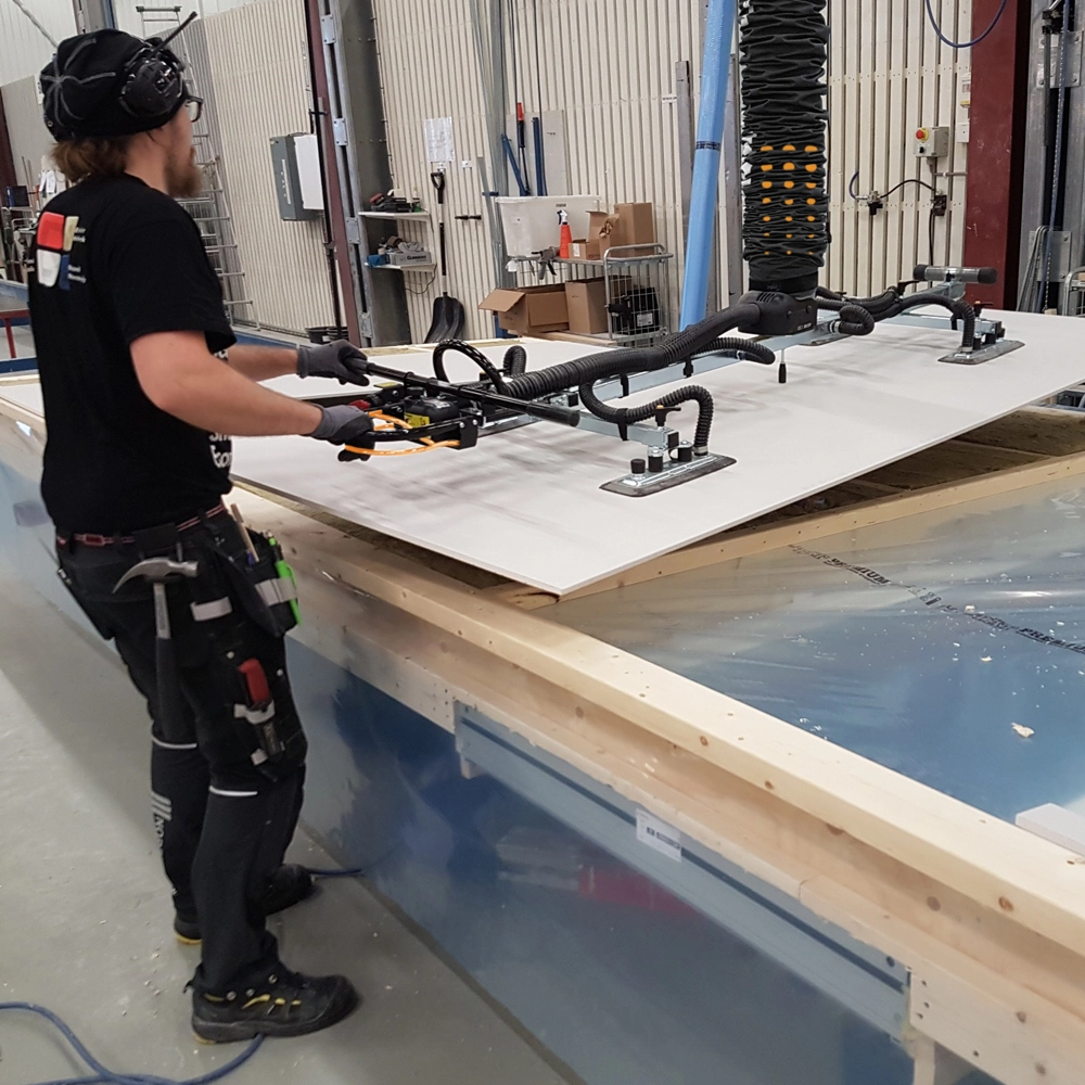 vacuum panel lifter lifting a sheet of wood onto a workbench
