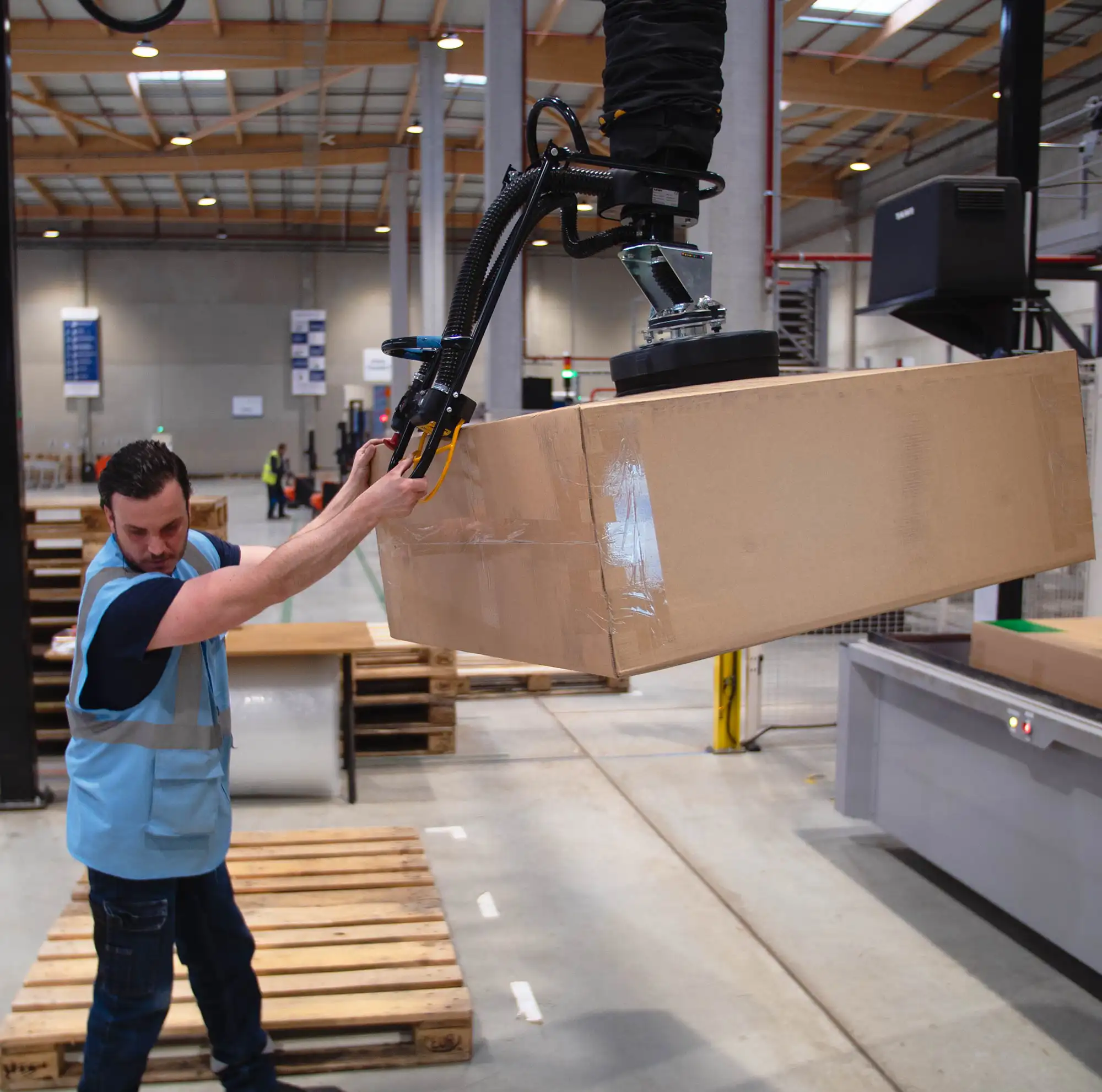 Logistics worker uses TAWI Vacuum Lifters for lifting heavy boxes