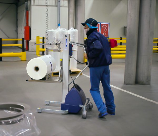 man pushing lifting trolley loaded with roll of plastic film