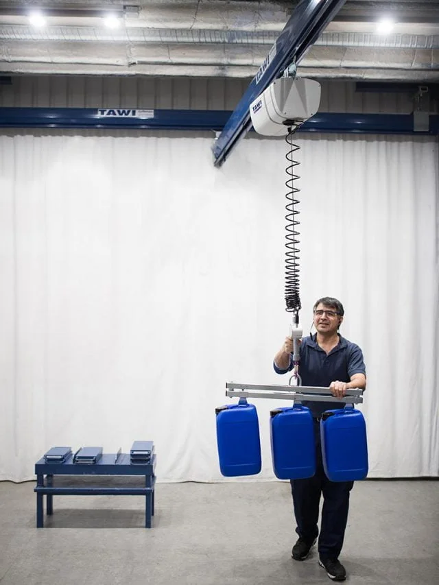 man lifting cannisters with wire hoist