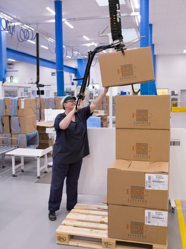Woman lifting up and packaging boxes above her shoulder using a handhold vacuum lifter