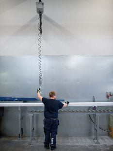 Man lifting metal profiles with hoist lift