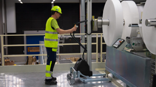 Man lifting and moving big plastic roll using a handhold vacuum lifter