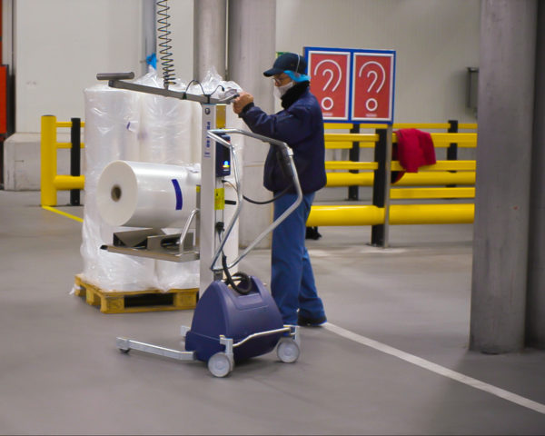 man lifting roll onto lifting trolley using a wire hoist