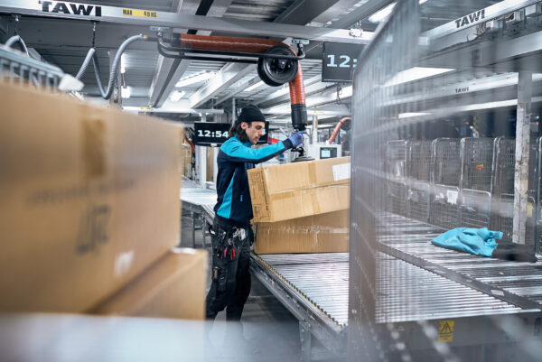 Packages being lifted with a vaccum lifter from conveyor to pallet at Postnord´s logistics centre