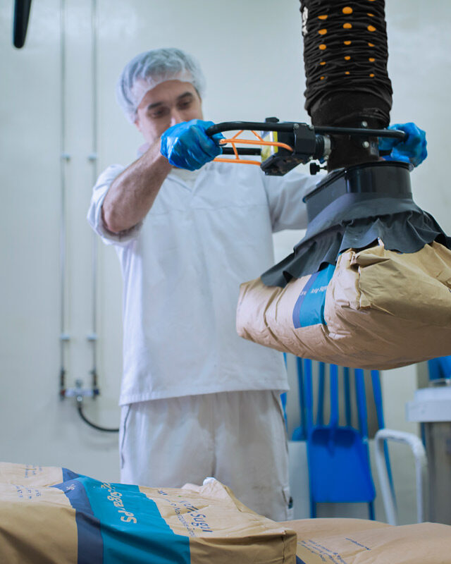 man lifting paper sack using handheld vacuum lifter in food industry