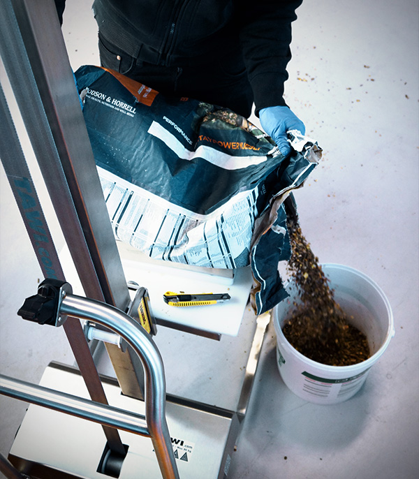 Sack being emptied from a stainless steel lifting cart with platform