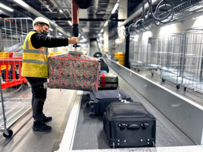 An employee using a vacuum lifter to help load and unload bags and other cargo