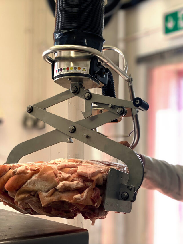 Operator lifting unpacked meat ergonomically with a stainless steel vacuum lift