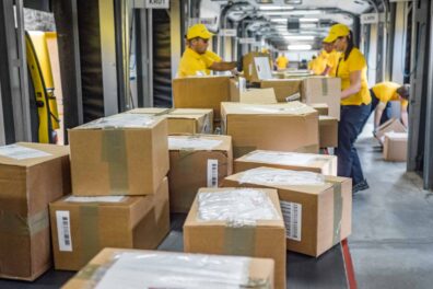 Lagermedarbejdere sorterer kasser på et transportbånd
