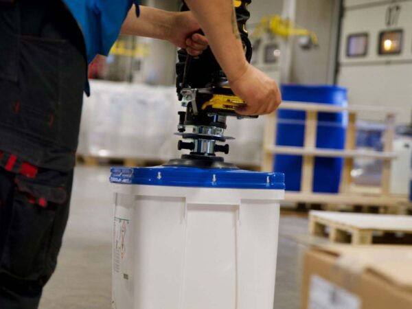 warehouse health and safety: Person in a warehouse palletizing a canister with the use of a TAWI vacuum lifter
