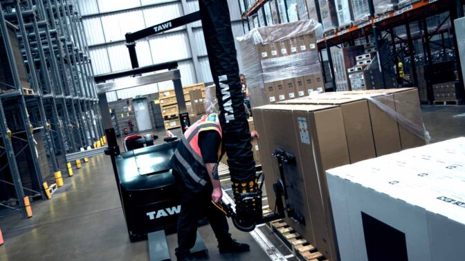 Warehouse worker using mobile vacuum lifter to lift a big box